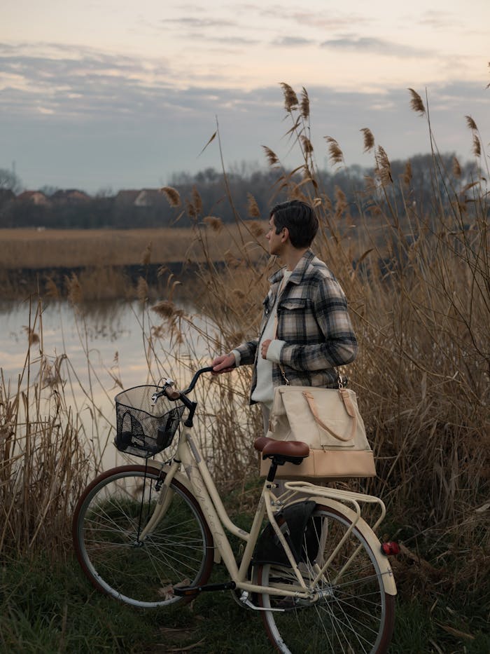 A person with a bicycle enjoys a peaceful sunset by the lakeside, surrounded by nature.